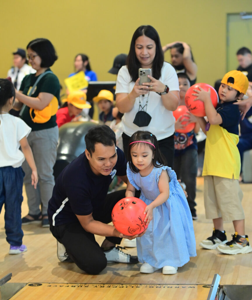 A child of an SM Prime employee learns how to bowl at the SM Bowling Center during the SM Prime Kids event, promoting family bonding.
