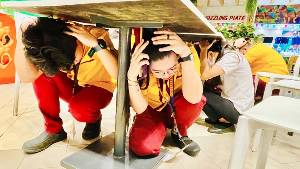 Agency personnel do the duck, cover, and hold during the nationwide simultaneous earthquake drill at SM City Marilao.