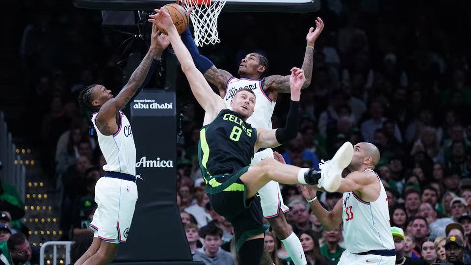 GRITTY: Celtics center Kristaps Porzingis (8) reaches for the passed ball against Clippers guard Kevin Porter Jr. (77).