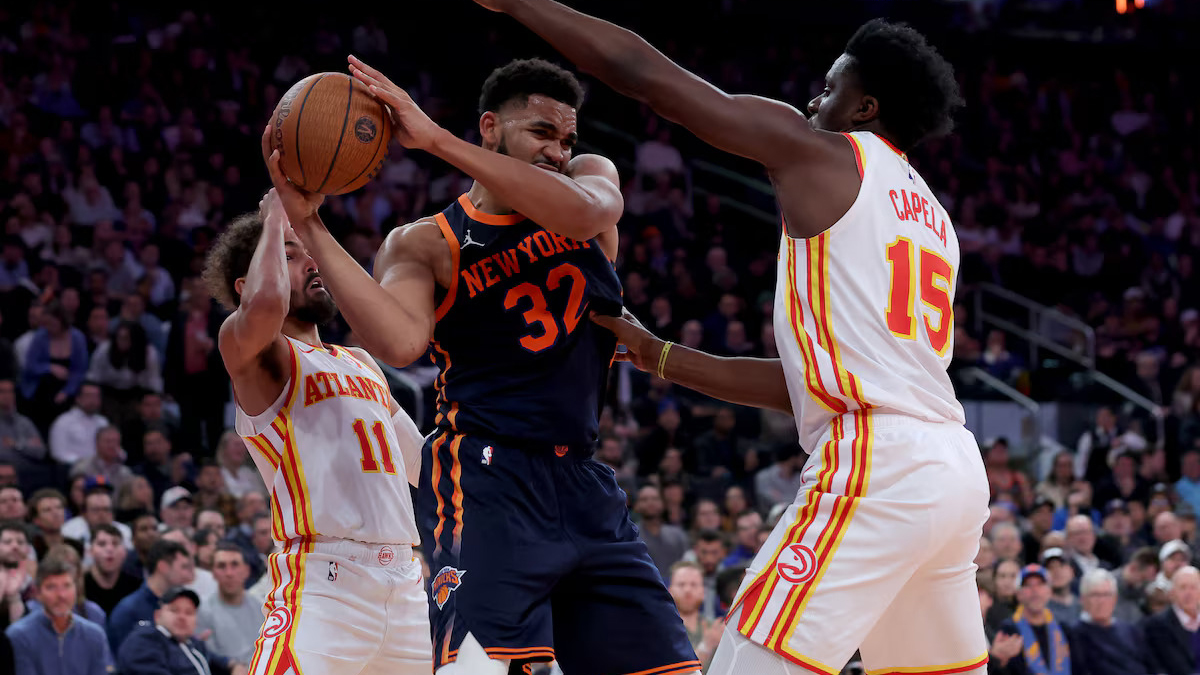 DOUBLE TEAMED: Knicks center Karl-Anthony Towns (32) controls the ball against Hawks guard Trae Young (11) and center Clint Capela (15) in yesterday’s game.