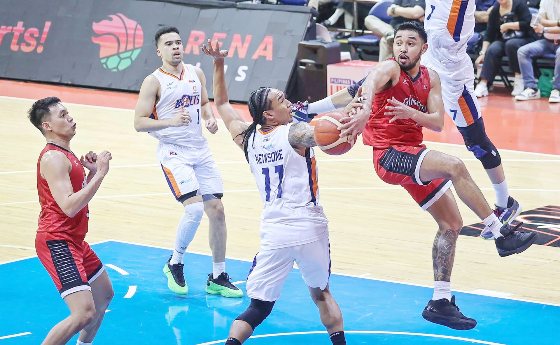 WILY: Ginebra rookie playmaker RJ Abarrientos passes the ball off Meralco star Chris Newsome in last Wednesday night’s game won by the Kings 100-92.