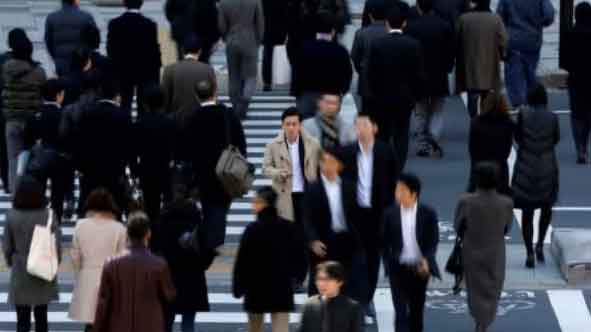 Pedestrians cross a street at a business district in Tokyo, Japan.