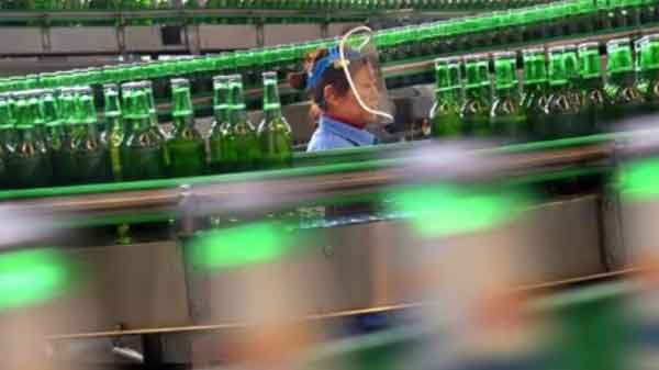 A woman works at the production line at a beer factory in Zibo, Shandong province, China.